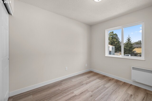 unfurnished room featuring a textured ceiling, light wood-type flooring, and radiator