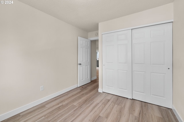 unfurnished bedroom with a closet, light hardwood / wood-style floors, and a textured ceiling