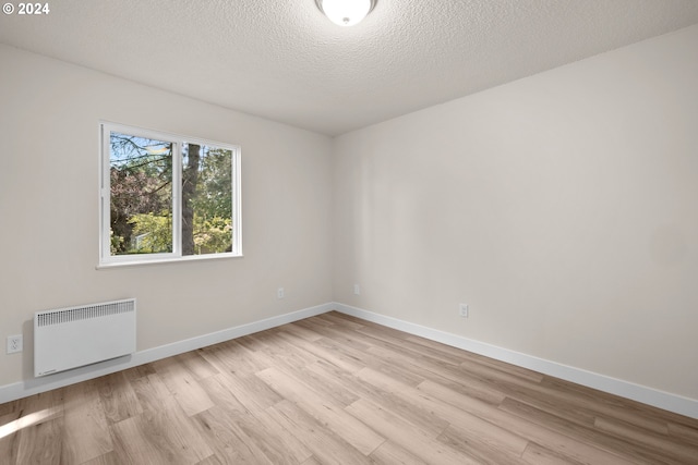 unfurnished room featuring light hardwood / wood-style floors, radiator heating unit, and a textured ceiling