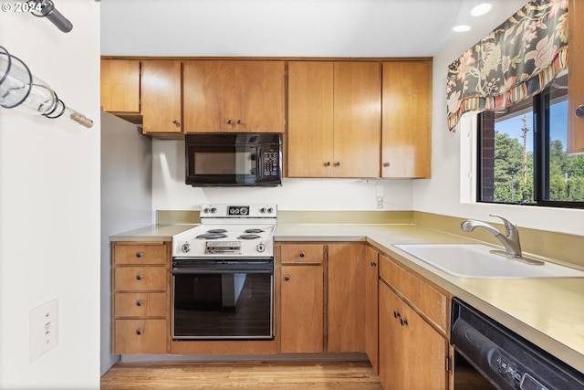 kitchen featuring sink, black appliances, and light wood-type flooring