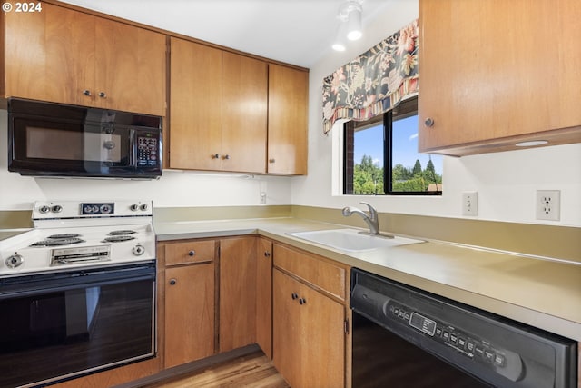 kitchen with light wood-type flooring, sink, and black appliances