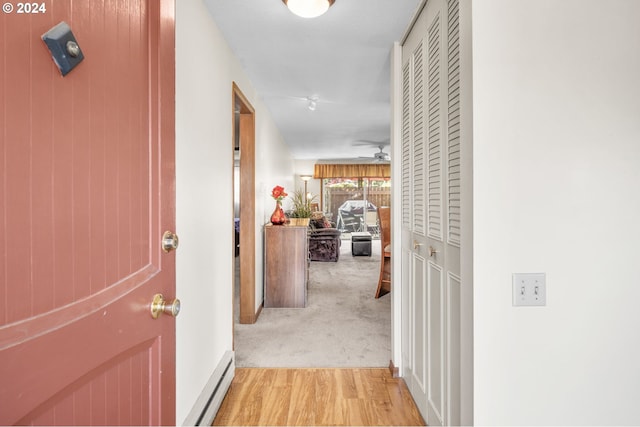 corridor featuring light colored carpet and a baseboard heating unit