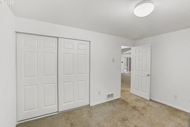 unfurnished bedroom with light carpet, a closet, and a textured ceiling