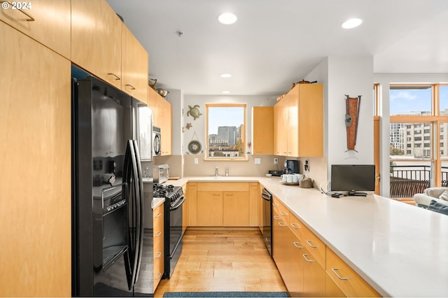 kitchen with black appliances, light brown cabinetry, and light wood-type flooring