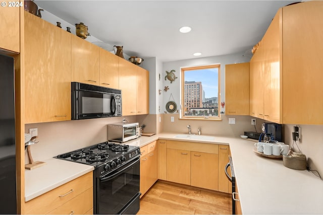 kitchen featuring light brown cabinets, light hardwood / wood-style flooring, black appliances, and sink