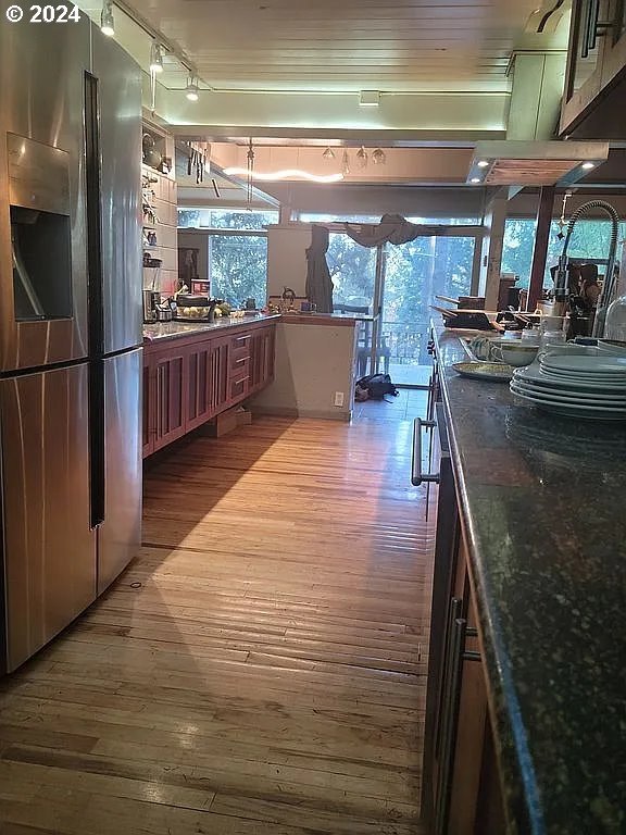 kitchen featuring hardwood / wood-style flooring, stainless steel refrigerator with ice dispenser, and dark stone counters