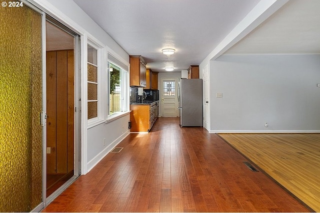 kitchen with stainless steel fridge, sink, dark wood-type flooring, and tasteful backsplash