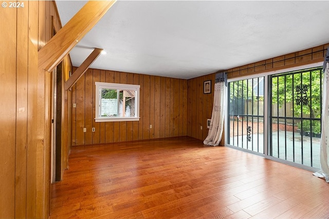 unfurnished room featuring hardwood / wood-style flooring and wooden walls