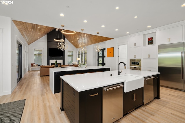 kitchen with wooden ceiling, a kitchen island with sink, hanging light fixtures, a large fireplace, and stainless steel appliances