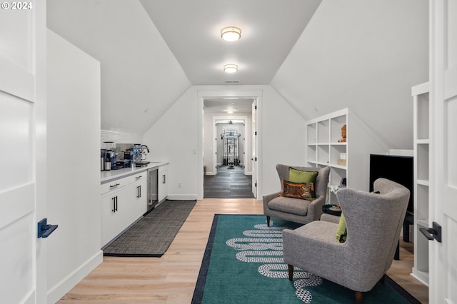 sitting room with hardwood / wood-style floors, built in features, lofted ceiling, and sink