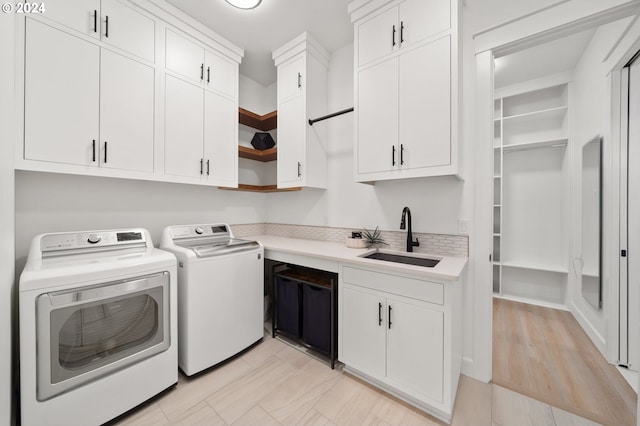 laundry area with washer and dryer, cabinets, and sink