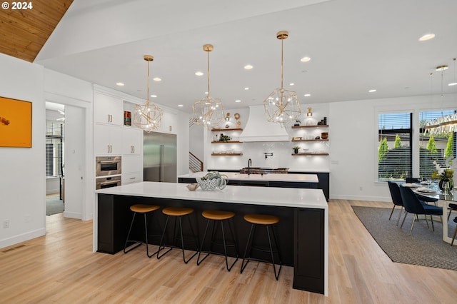 kitchen with stainless steel built in refrigerator, hanging light fixtures, and a large island