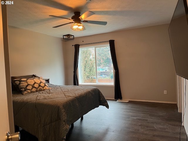 bedroom featuring ceiling fan, dark hardwood / wood-style flooring, and a textured ceiling