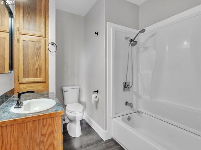 724 Kayla Way, Monmouth, OR 97361 - full bath with toilet, vanity, wood finished floors, washtub / shower combination, and baseboards
