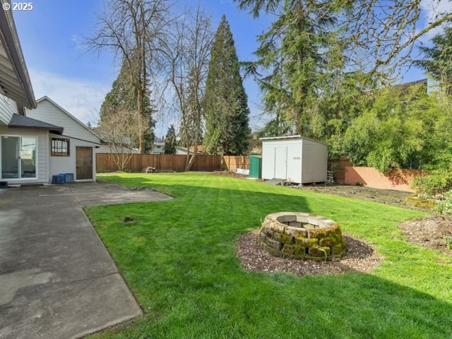 724 Kayla Way, Monmouth, OR 97361 - view of yard with an outdoor fire pit, an outdoor structure, a fenced backyard, and a shed