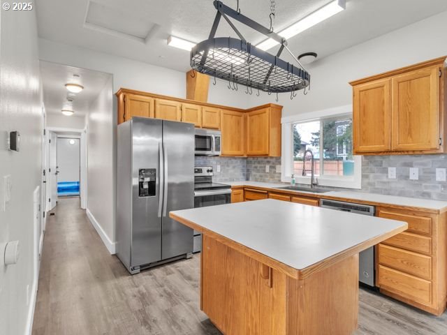 724 Kayla Way, Monmouth, OR 97361 - kitchen with light countertops, appliances with stainless steel finishes, a sink, light wood-type flooring, and a center island