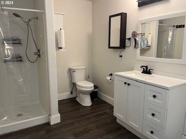 bathroom featuring hardwood / wood-style flooring, vanity, toilet, and walk in shower