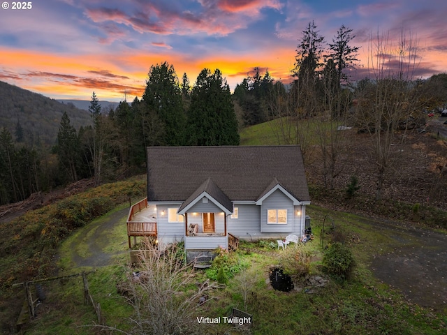 view of front of home featuring roof with shingles and a wooded view