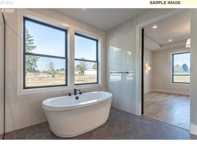 bathroom featuring a tub, a healthy amount of sunlight, and hardwood / wood-style floors