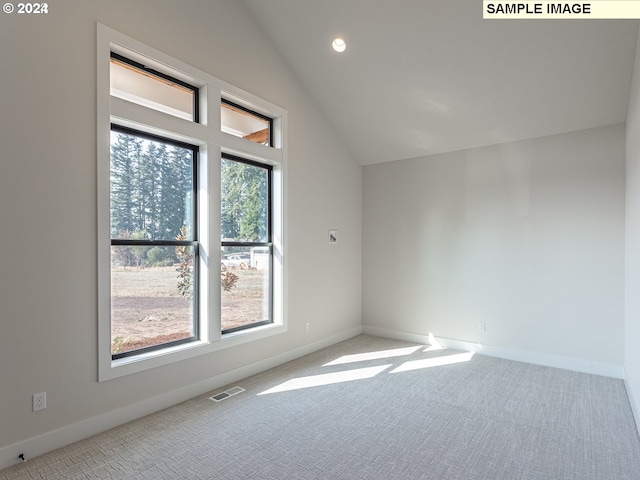 spare room featuring light carpet and lofted ceiling