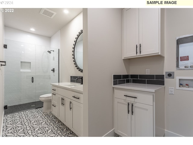 interior space with toilet, a shower with shower door, and vanity