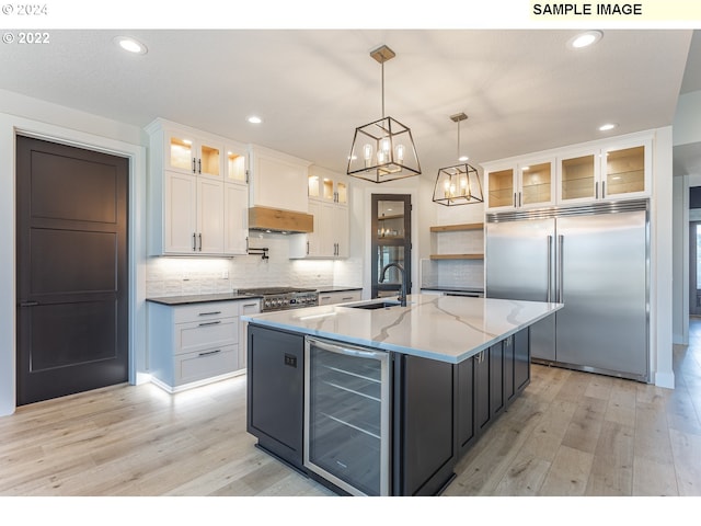 kitchen featuring wine cooler, white cabinets, decorative light fixtures, high quality appliances, and sink