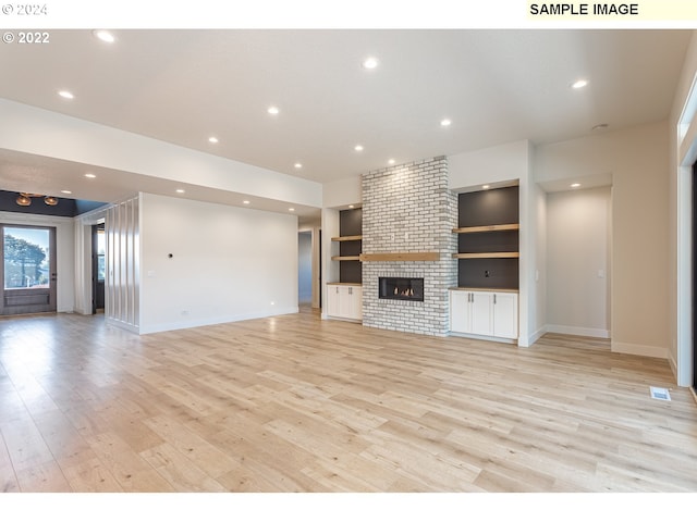 unfurnished living room featuring built in shelves, light hardwood / wood-style flooring, and a fireplace