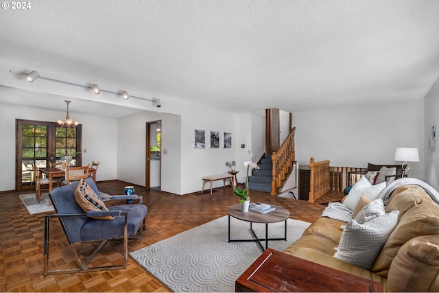 living room with a textured ceiling, an inviting chandelier, and stairs