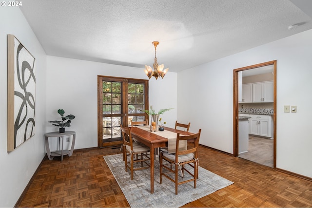 dining room featuring a textured ceiling, baseboards, and a notable chandelier