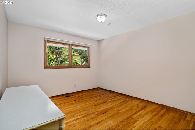 unfurnished room featuring a textured ceiling, light wood-type flooring, and visible vents