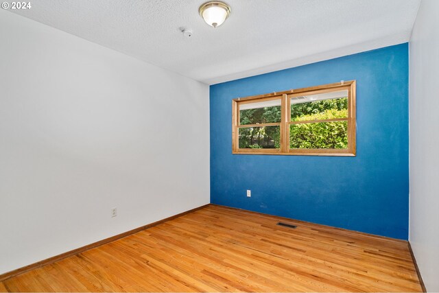 empty room with light hardwood / wood-style floors and a textured ceiling