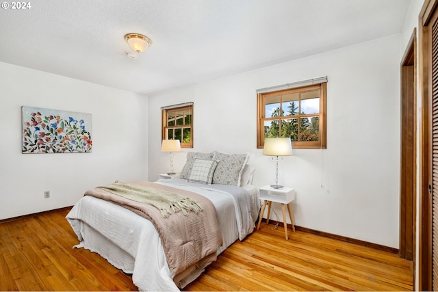 bedroom featuring baseboards, multiple windows, and light wood finished floors