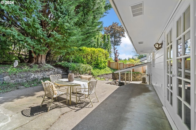 view of patio / terrace with outdoor dining area, fence, and visible vents