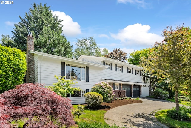 view of front of property with driveway, a chimney, and an attached garage