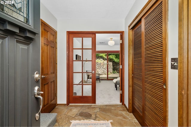 doorway with french doors, light colored carpet, and a textured ceiling