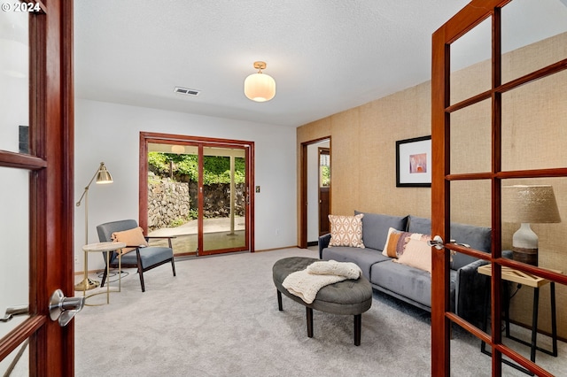 living area featuring baseboards, a textured ceiling, visible vents, and carpet flooring