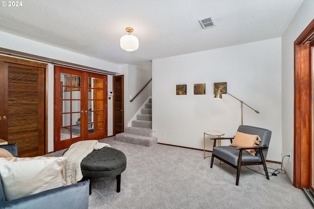 living area with a textured ceiling, carpet floors, visible vents, french doors, and stairway