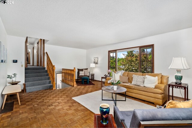 living room featuring a brick fireplace, light parquet flooring, and a textured ceiling