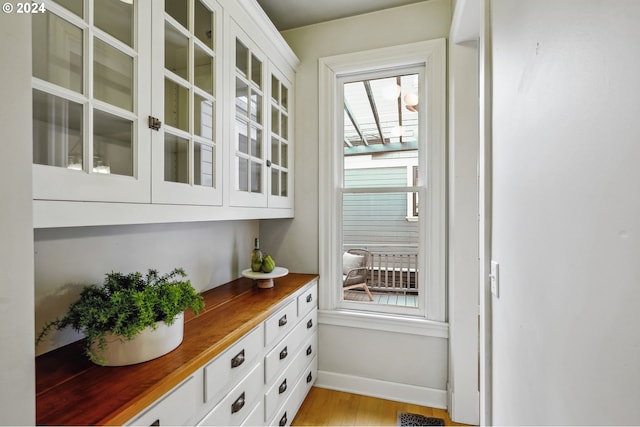 bar featuring white cabinetry and light hardwood / wood-style flooring