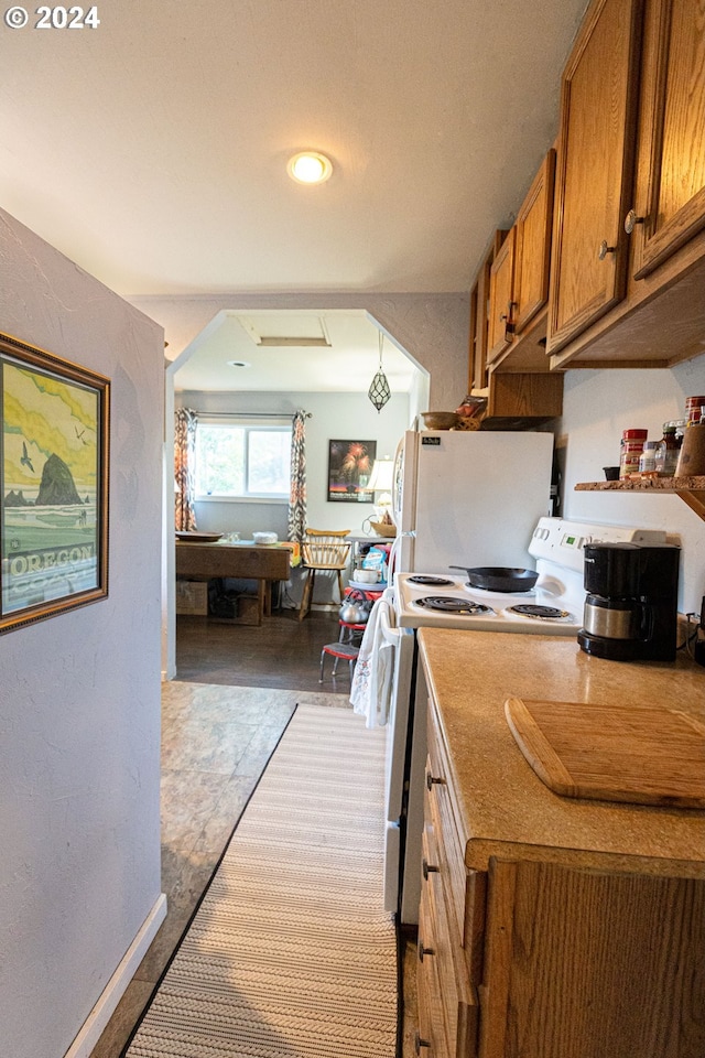 kitchen featuring white appliances, brown cabinetry, light countertops, and a textured wall