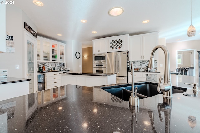 kitchen with pendant lighting, appliances with stainless steel finishes, white cabinetry, decorative backsplash, and dark stone counters