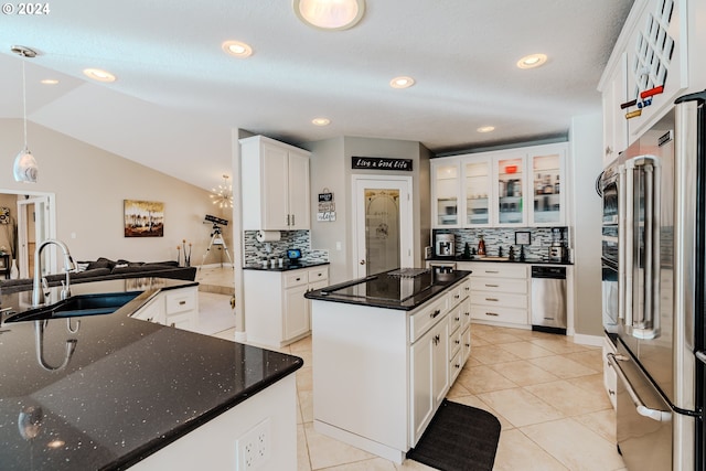 kitchen with sink, white cabinetry, hanging light fixtures, high quality fridge, and a kitchen island