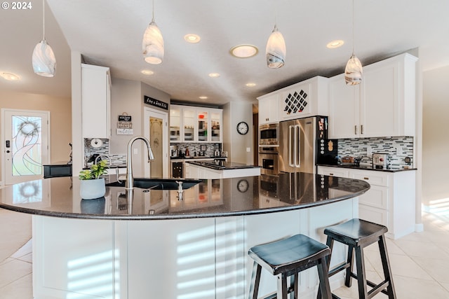 kitchen with stainless steel appliances, white cabinetry, sink, and decorative light fixtures