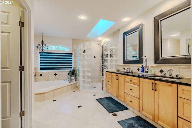 bathroom with backsplash, a skylight, vanity, tile patterned floors, and shower with separate bathtub