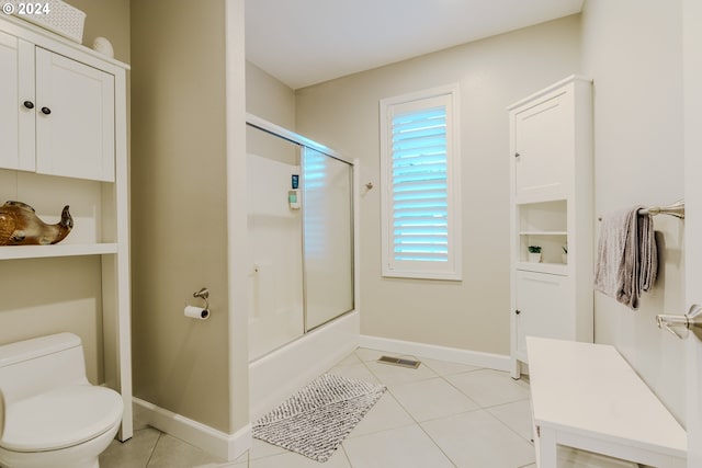 bathroom with toilet, tile patterned floors, and shower / bath combination with glass door