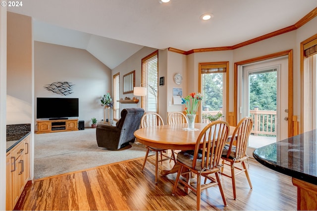 dining room with light hardwood / wood-style flooring, a wealth of natural light, lofted ceiling, and crown molding