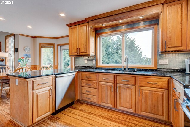 kitchen featuring appliances with stainless steel finishes, kitchen peninsula, light wood-type flooring, and sink