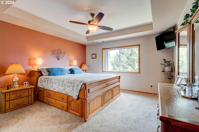 carpeted bedroom with ceiling fan and a raised ceiling