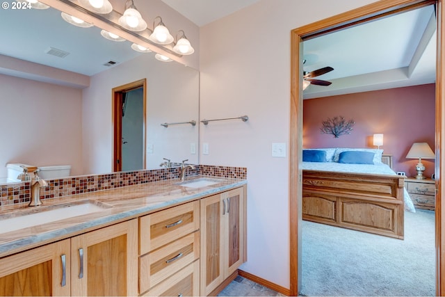 bathroom with ceiling fan, vanity, backsplash, and toilet