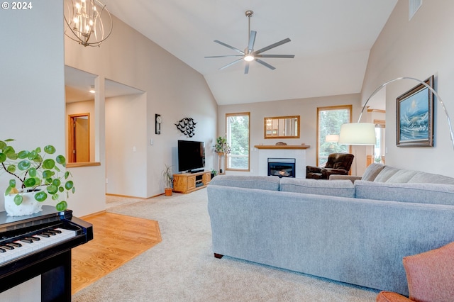 living room with carpet floors, ceiling fan with notable chandelier, and high vaulted ceiling